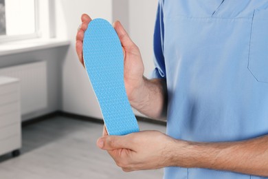 Photo of Male orthopedist showing insole in hospital, closeup