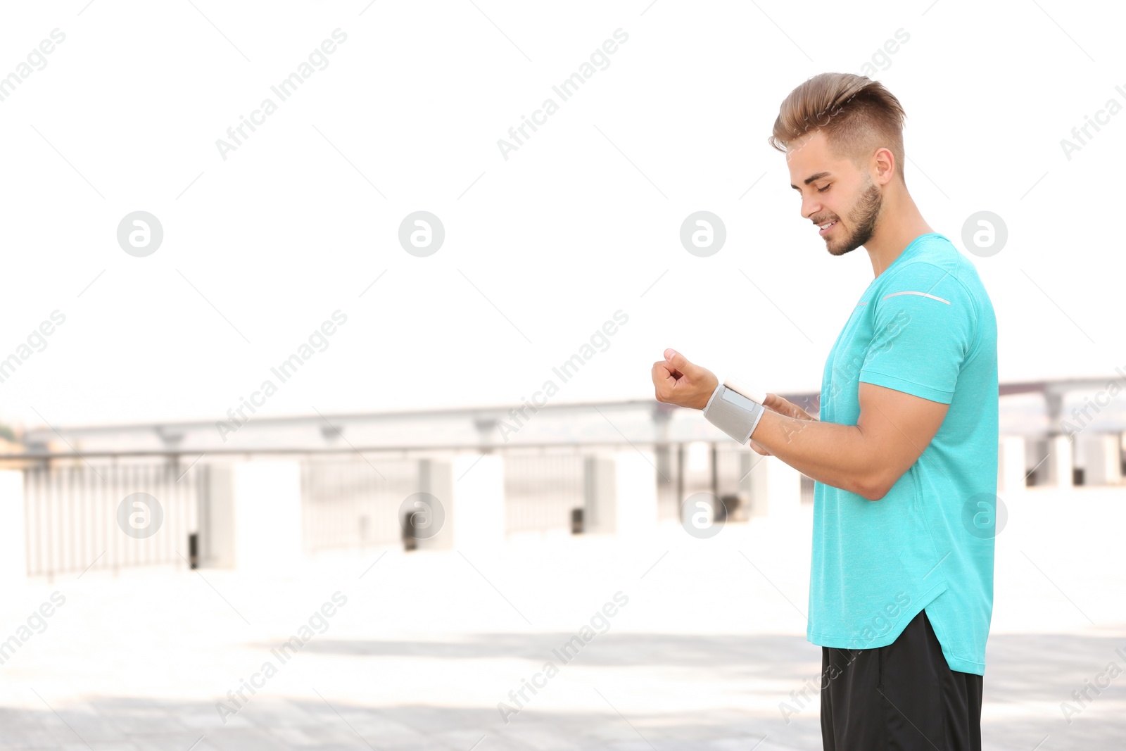 Photo of Young man checking pulse outdoors on sunny day