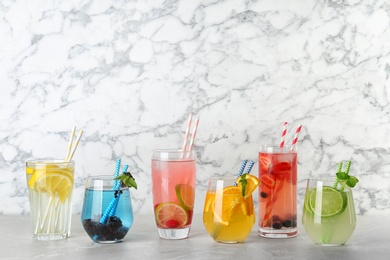 Photo of Glasses with lemonades on table against marble background