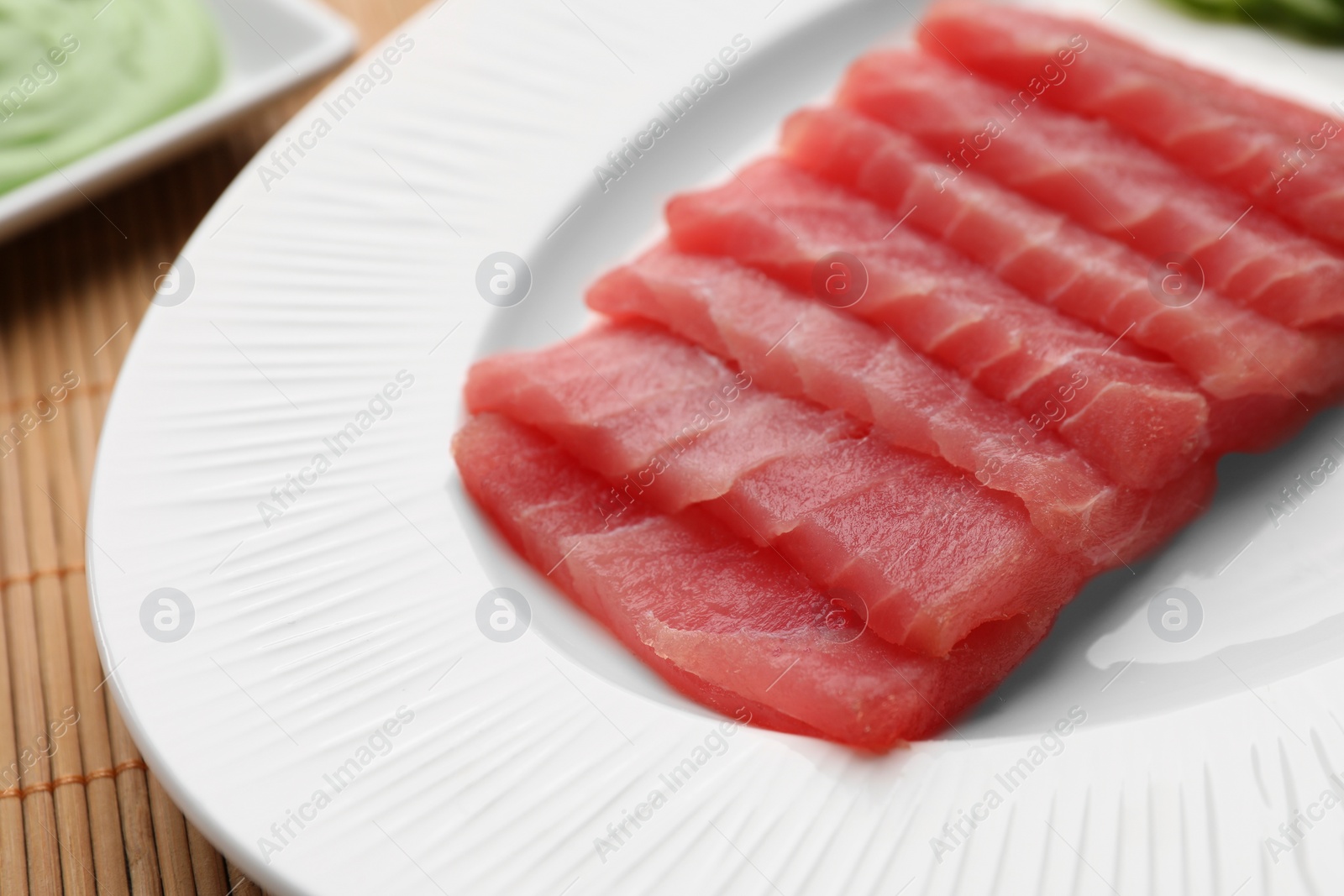 Photo of Tasty sashimi (pieces of fresh raw tuna) on white plate, closeup