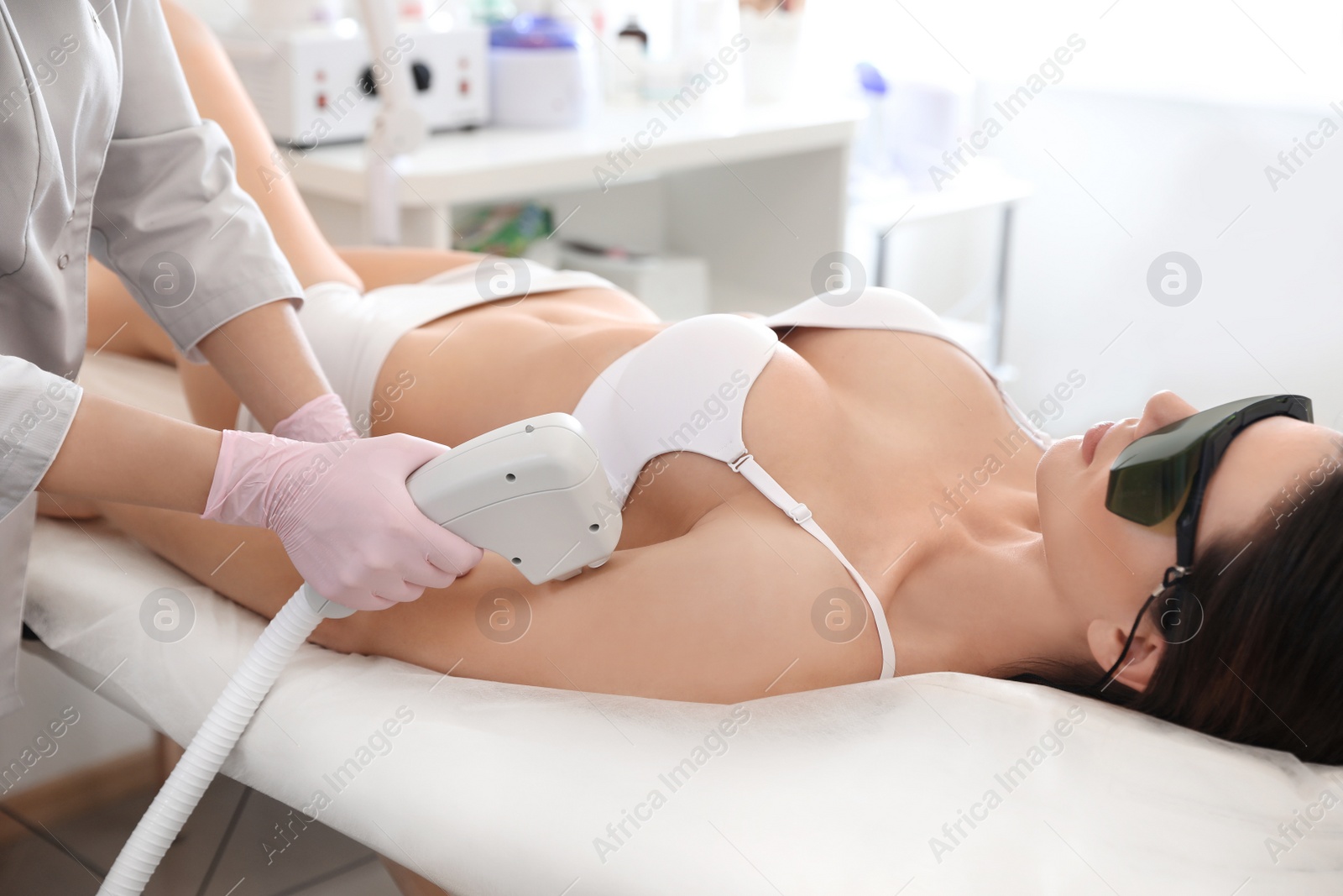 Photo of Young woman undergoing laser epilation procedure in beauty salon