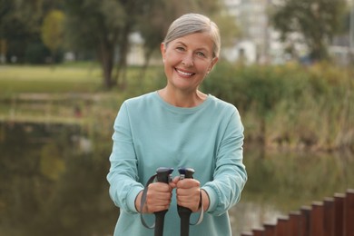 Photo of Senior woman with Nordic walking poles outdoors