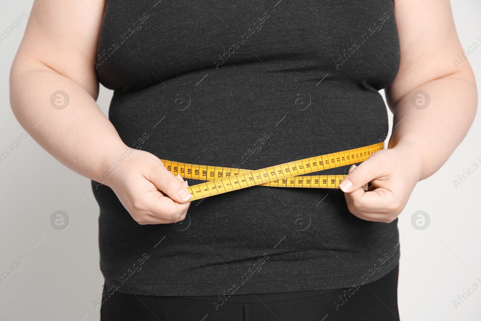 Photo of Overweight woman with measuring tape on light background