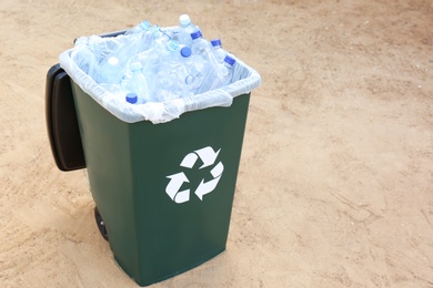 Many used plastic bottles in trash bin outdoors, space for text. Recycling problem