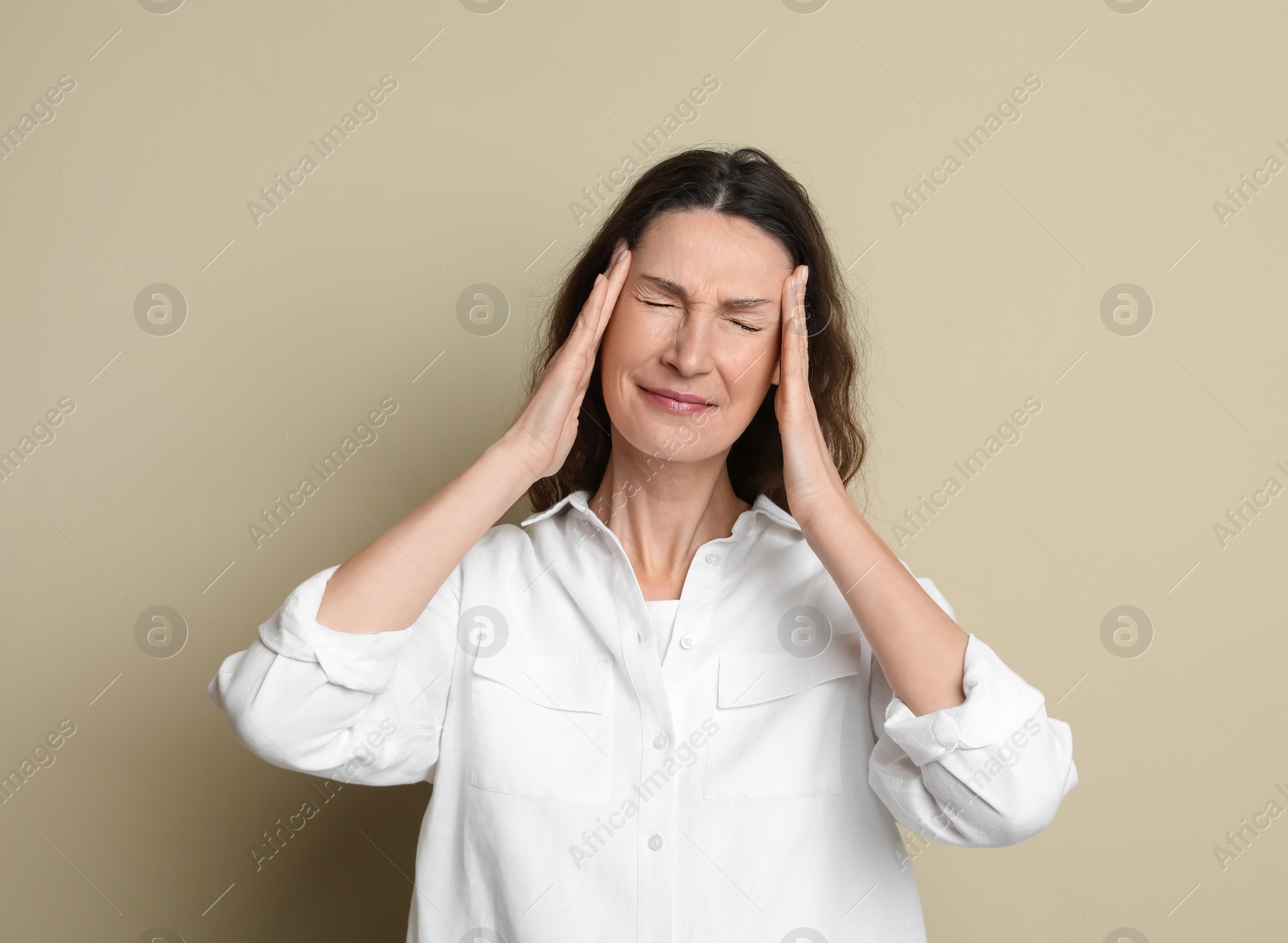 Photo of Mature woman suffering from headache on beige background