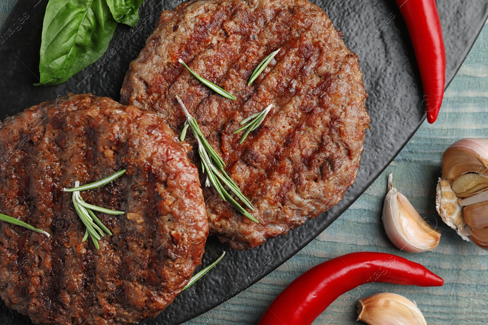 Photo of Grilled meat cutlets for burger on blue wooden table, top view