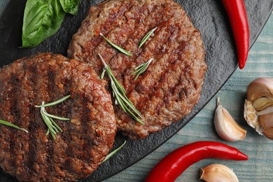 Photo of Grilled meat cutlets for burger on blue wooden table, top view