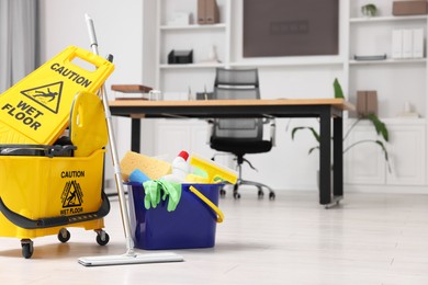 Cleaning service. Mop, bucket with supplies and wet floor sign in office, space for text