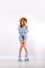 Photo of Young woman with retro roller skates near white wall