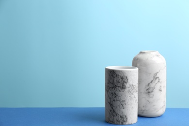 Stylish empty ceramic vases on table against light blue background, space for text