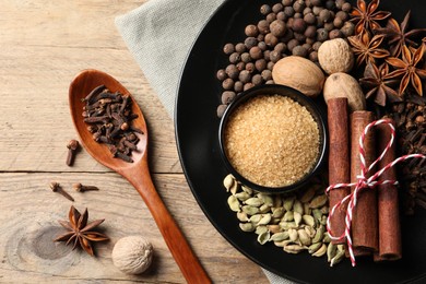 Dishware with different spices on wooden table, flat lay