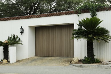 Photo of White wall with closed gates and palms. Exterior design