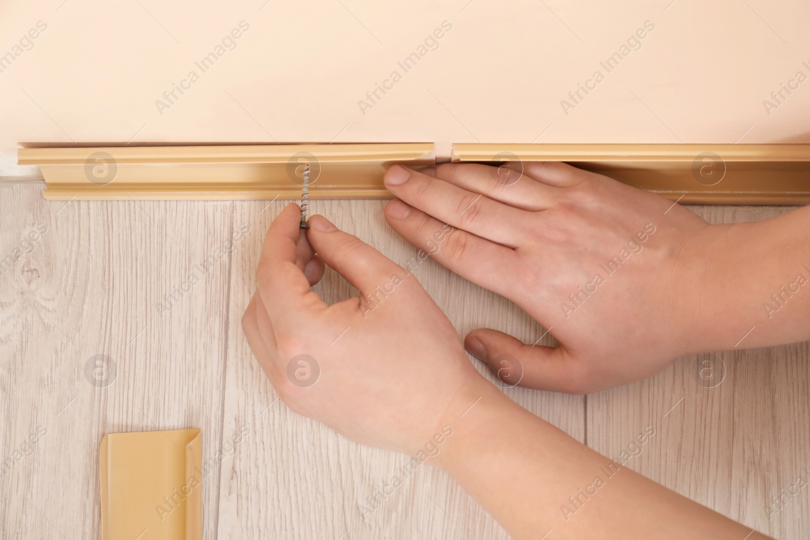 Photo of Man installing plinth on laminated floor in room, view from above