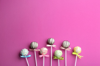 Different tasty cake pops on pink background, flat lay. Space for text