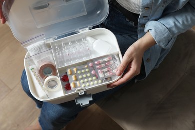 Photo of Woman holding first aid kit indoors, top view