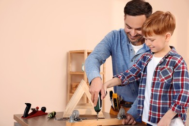 Photo of Father and son screwing wooden plank at home, space for text. Repair work