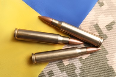Photo of Bullets and Ukrainian flag on military camouflage, flat lay