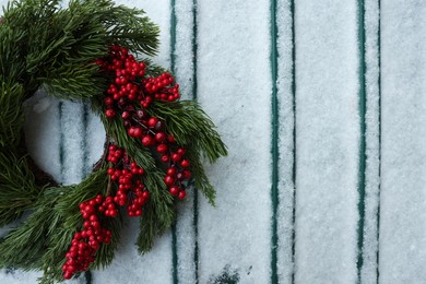 Beautiful Christmas wreath on metal surface covered with snow, top view. Space for text