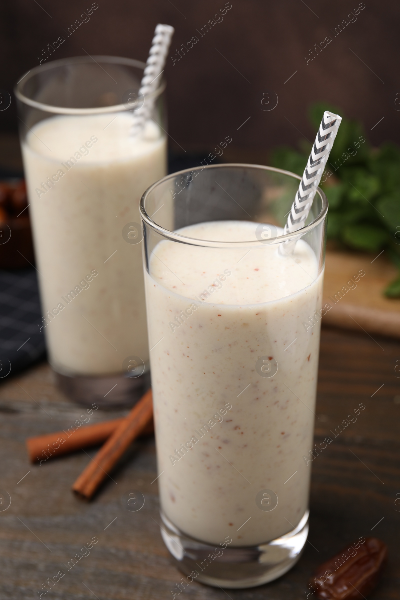 Photo of Glasses of delicious date smoothie, dried fruit and cinnamon sticks on wooden table, closeup