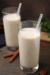 Photo of Glasses of delicious date smoothie, dried fruit and cinnamon sticks on wooden table, closeup