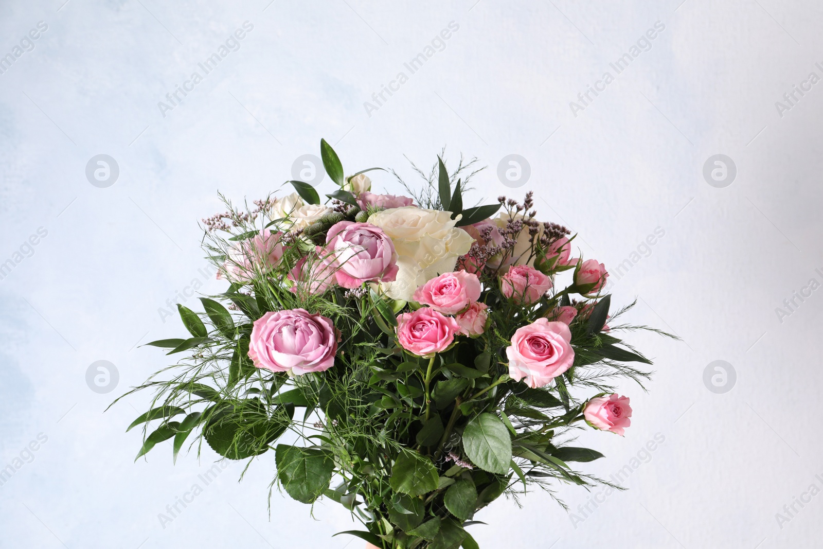 Photo of Beautiful bouquet with roses on light blue background