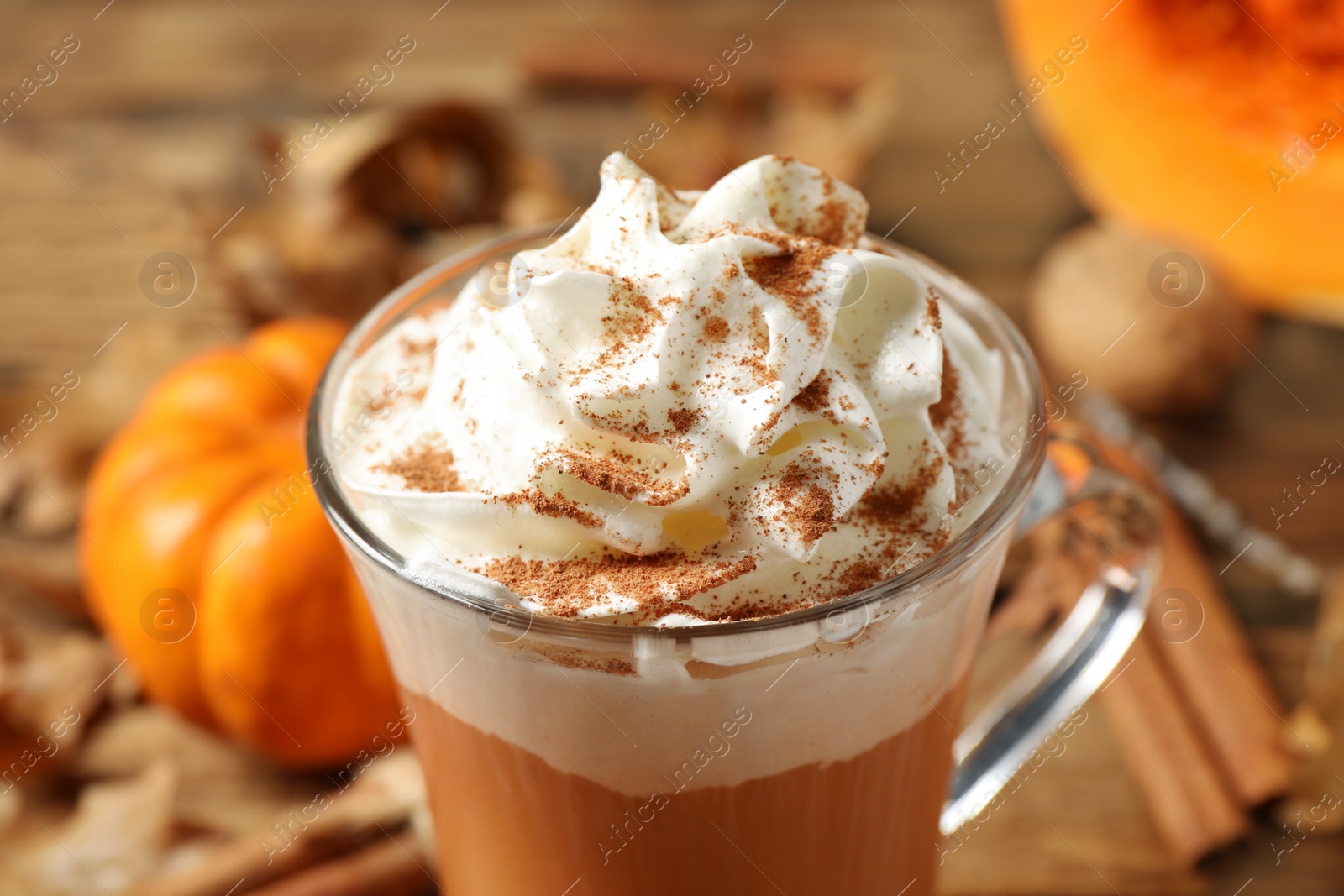 Photo of Delicious pumpkin latte with whipped cream on table, closeup