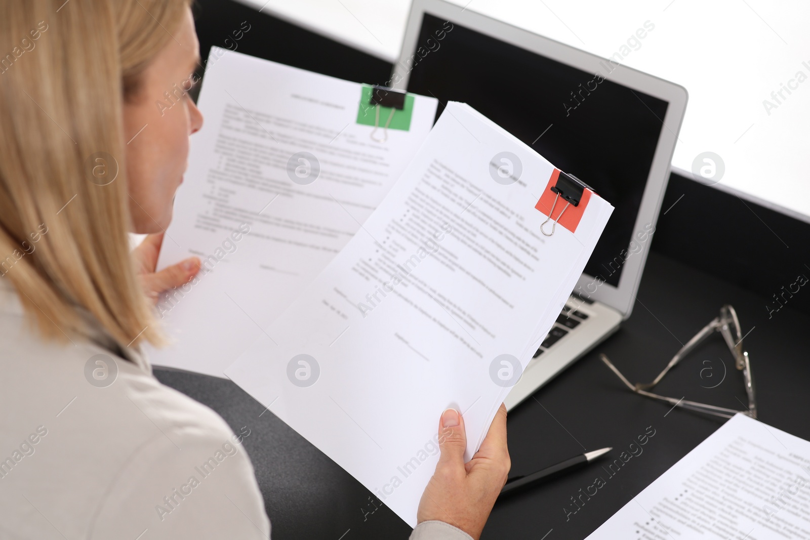 Photo of Businesswoman working with documents at dark table in office, closeup