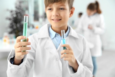 Photo of Smart pupil with test tubes at chemistry class, closeup