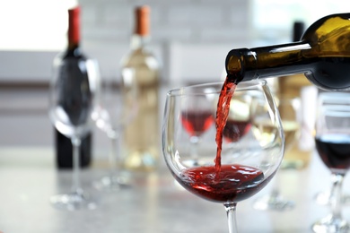 Photo of Pouring delicious red wine into glass on table