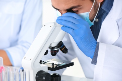 Photo of Male scientist working with microscope in laboratory, closeup. Research and analysis