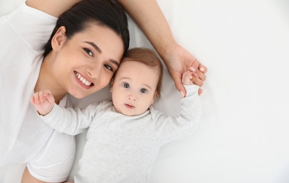 Photo of Portrait of mother with her cute baby lying on bed, top view