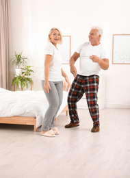 Photo of Happy mature couple dancing together in bedroom