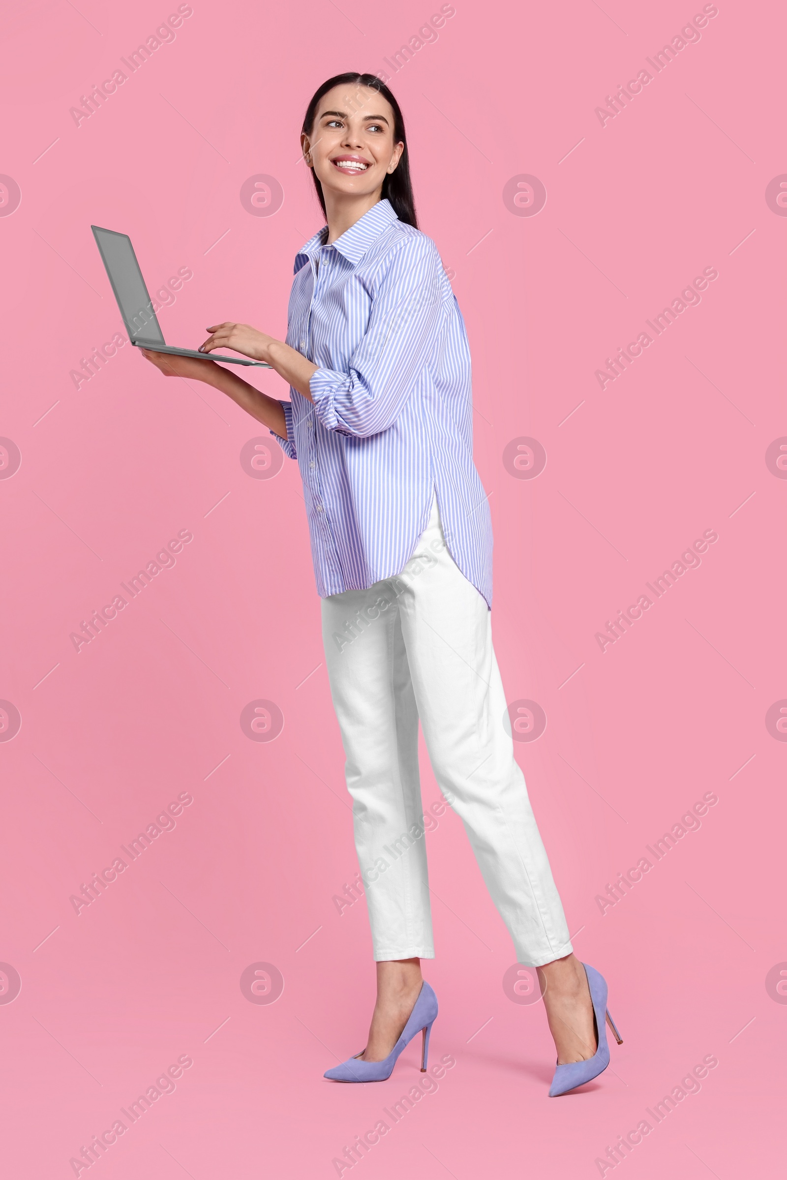 Photo of Happy woman with laptop on pink background