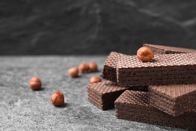 Delicious chocolate wafers and hazelnuts on grey table, closeup. Space for text