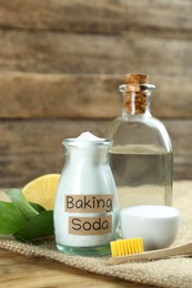 Bamboo toothbrush and jar of baking soda on wooden table