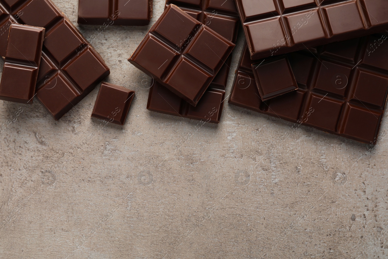 Photo of Delicious dark chocolate on grey table, flat lay. Space for text