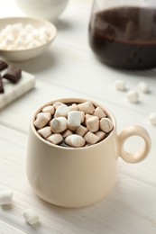 Cup of aromatic hot chocolate with marshmallows on white wooden table