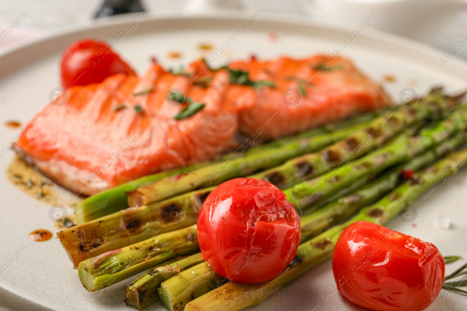 Photo of Tasty grilled asparagus, tomatoes and salmon on plate, closeup