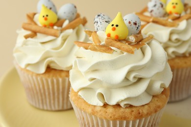 Photo of Tasty Easter cupcakes with vanilla cream on beige background, closeup