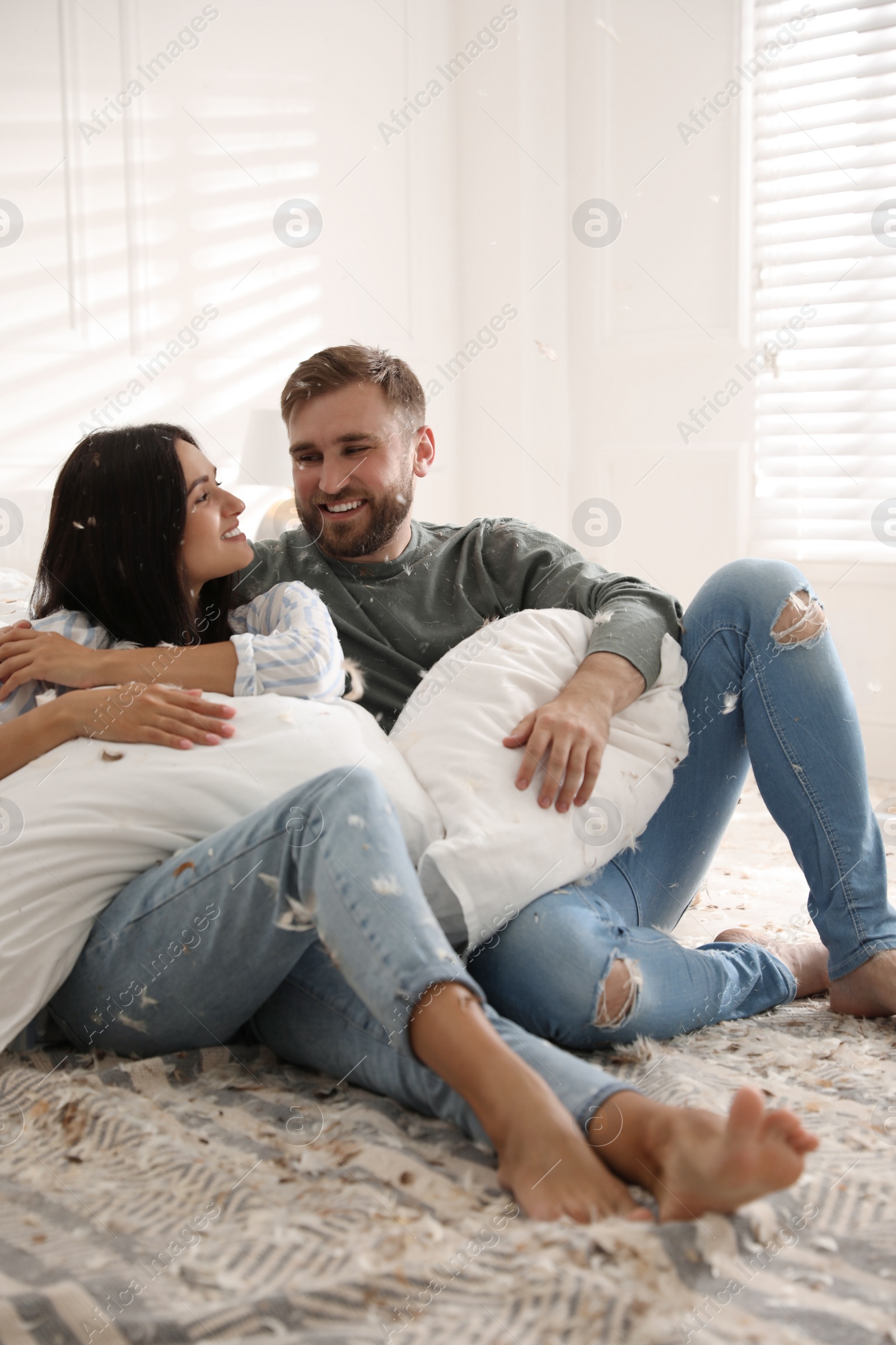 Photo of Happy young couple resting after fun pillow fight at home