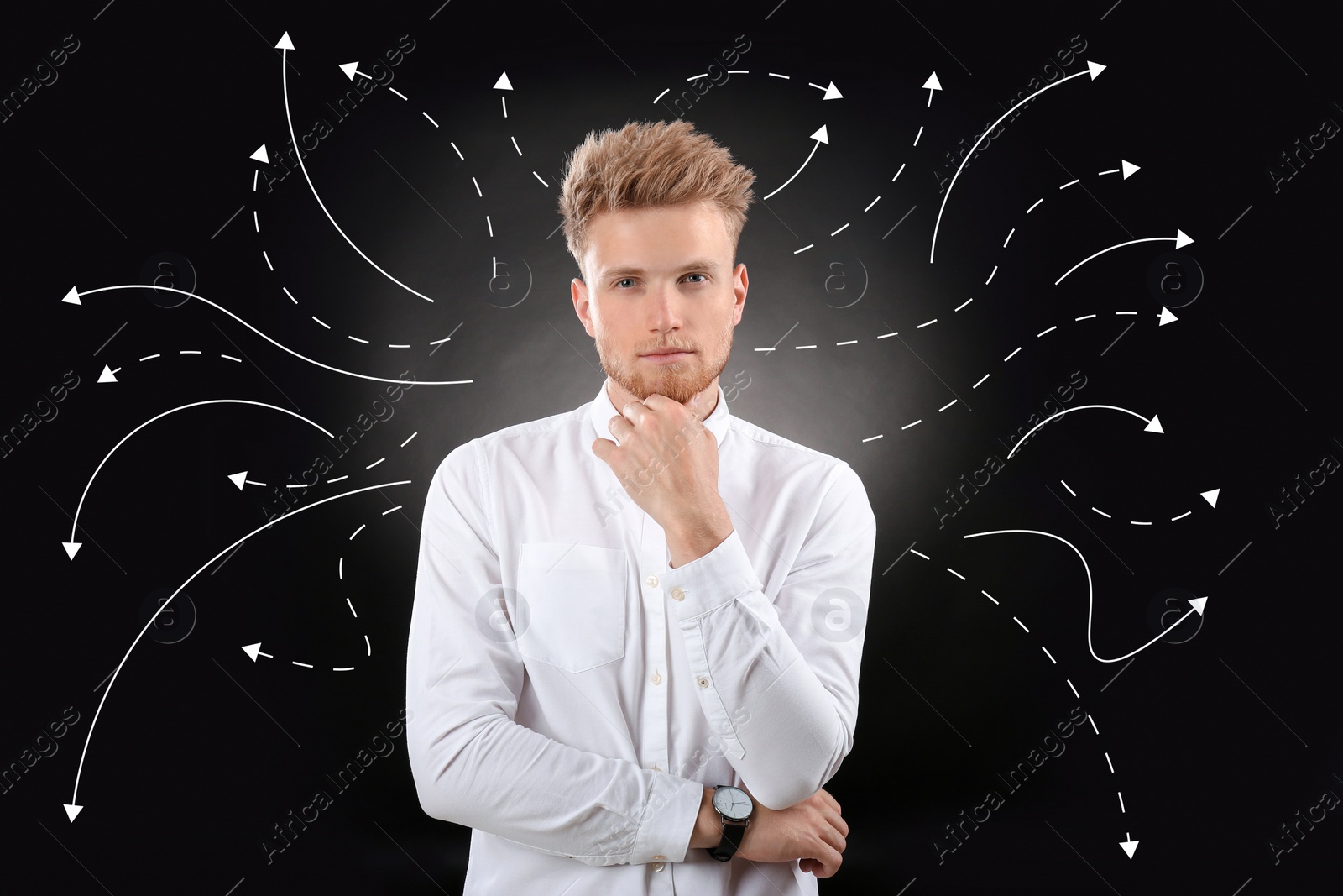 Image of Choice in profession or other areas of life, concept. Making decision, thoughtful young man surrounded by drawn arrows on black background