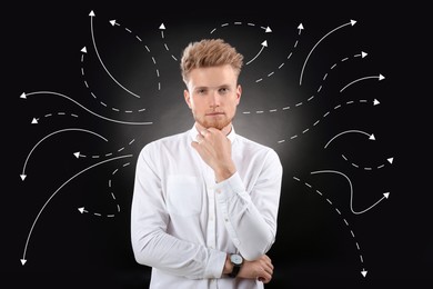 Image of Choice in profession or other areas of life, concept. Making decision, thoughtful young man surrounded by drawn arrows on black background