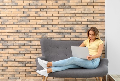 Photo of Beautiful woman with laptop on sofa indoors