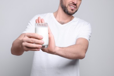 Photo of Man with glass of milk suffering from lactose intolerance on white background, closeup