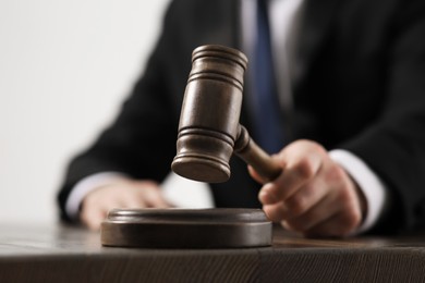 Photo of Law and justice. Closeup of judge with gavel at wooden table, selective focus