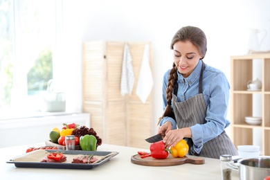 Photo of Professional female chef cutting pepper on table in kitchen