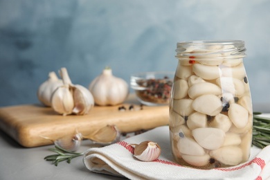 Photo of Composition with jar of pickled garlic on grey table against blue background. Space for text