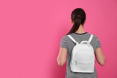 Young woman with stylish leather backpack on pink background, back view. Space for text