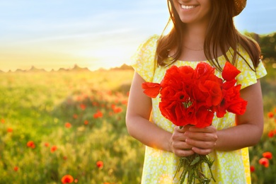Photo of Woman with bouquet of poppies in field on sunny day, closeup. Space for text