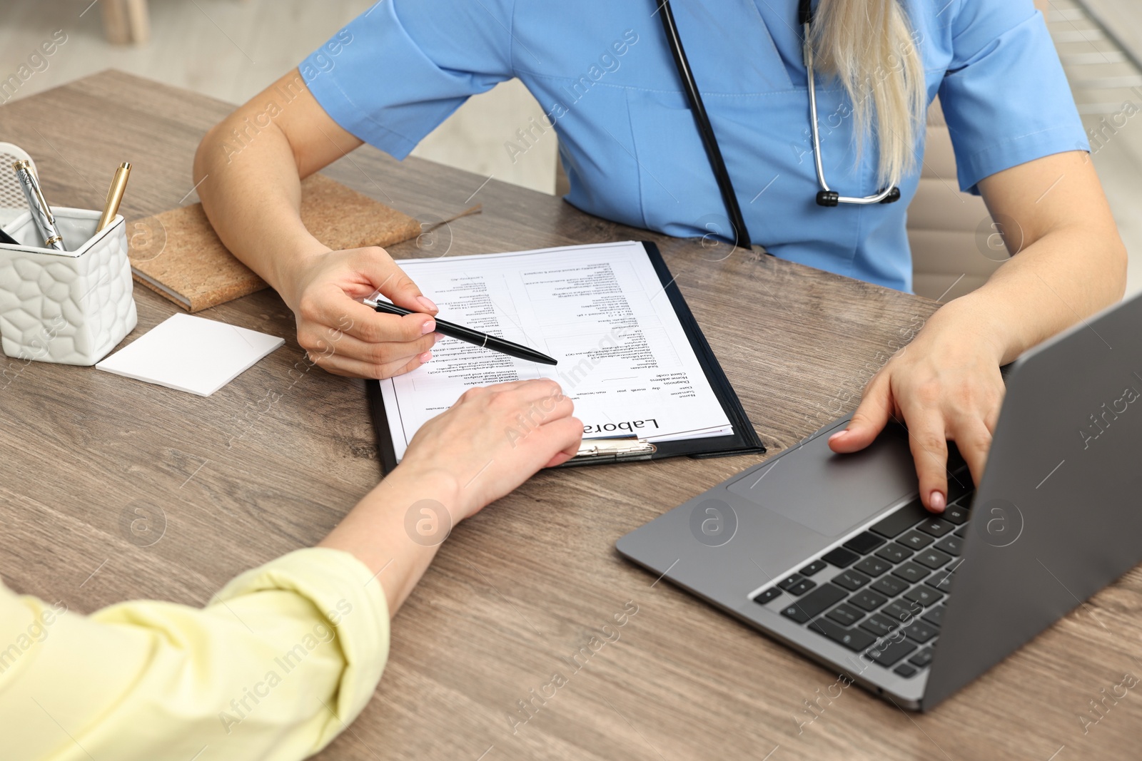 Photo of Doctor with results of laboratory test consulting pregnant patient in clinic, closeup